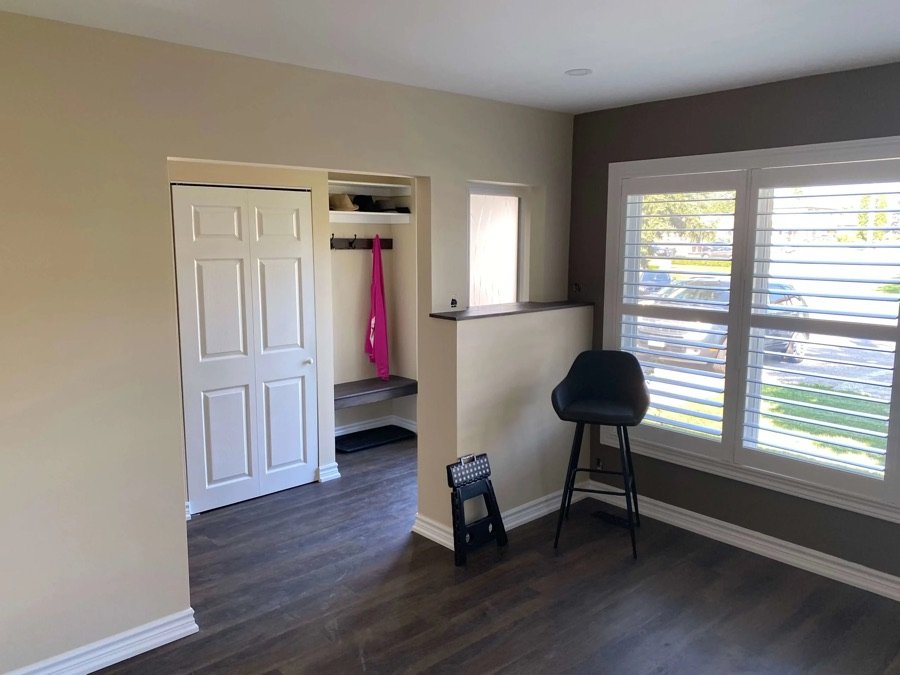 entryway with built in coat bench white closet door and window shutters