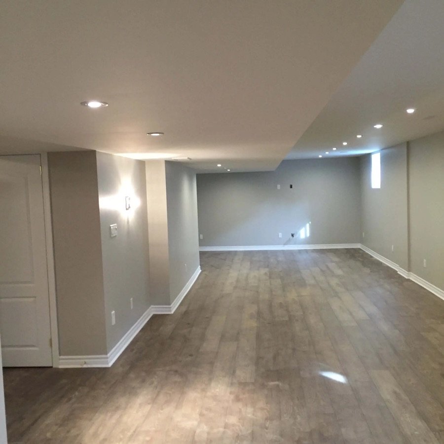 Renovated basement with light-tone vinyl plank flooring, recessed ceiling lights, and smooth finished walls in neutral paint tones