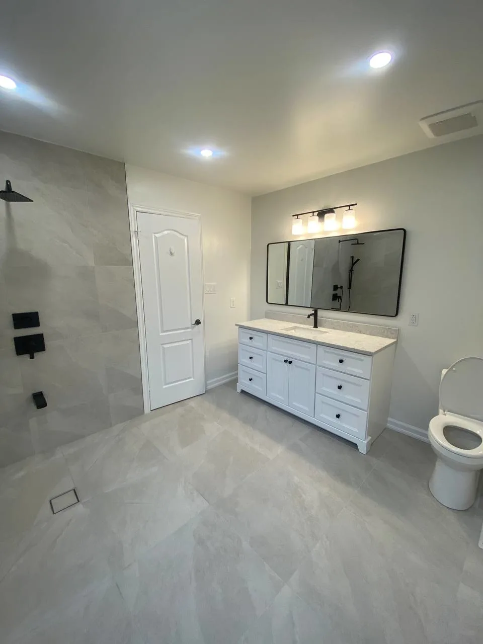 Spacious bathroom with freshly installed light grey ceramic floor tiles by RM Renovation, flooring and tiling contractors in Toronto, Ontario