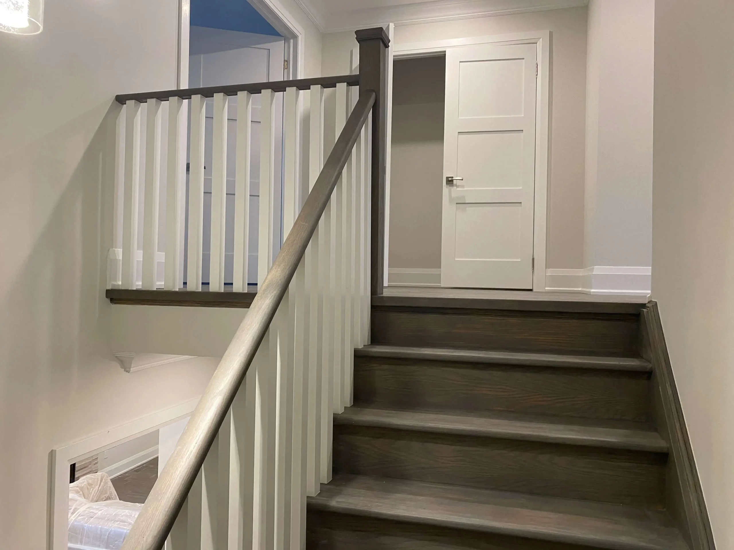 Newly renovated staircase and upper hallway with dark oak steps and white railings from a whole home renovation in the GTA