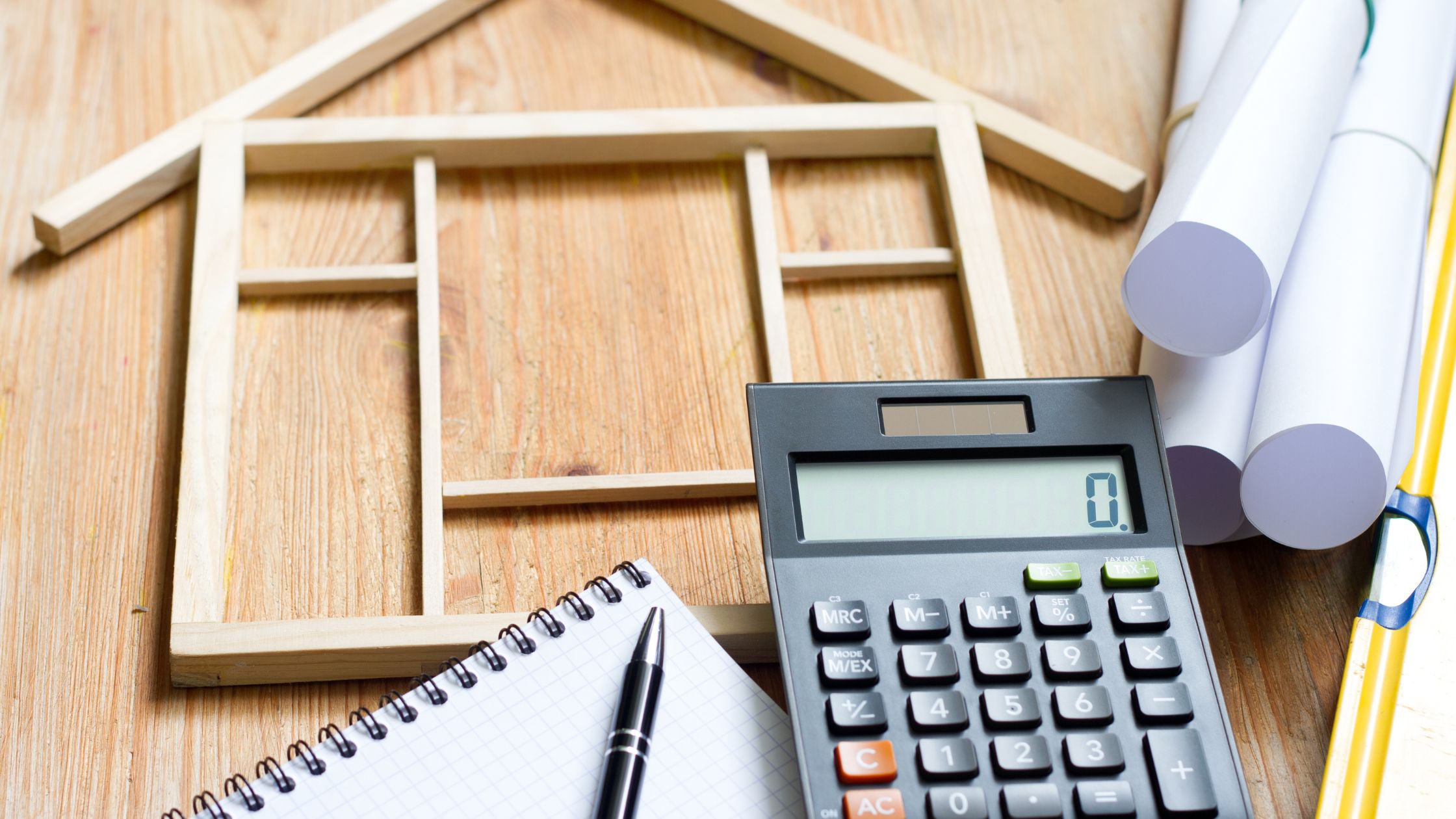 Budget planning tools with house layout model, calculator, and blueprints on a table, illustrating how to plan a full home renovation in Ontario.